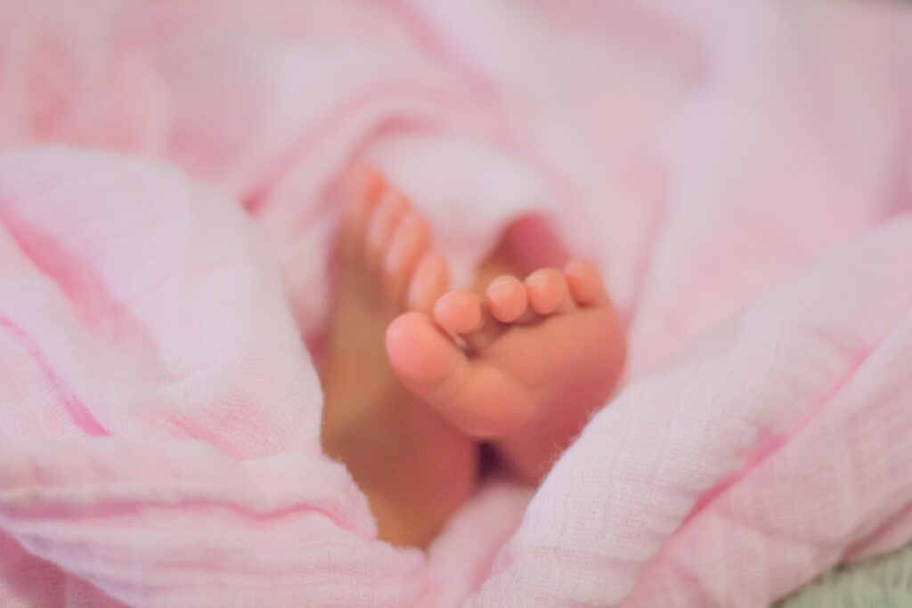 Füße eines Kleinkinds in einer rosa Decke