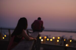 Frau guckt in die ferne, am Meer bei Sonnenuntergang