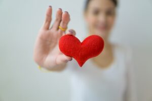 Frau mit einem Stoff-Herz in der Hand