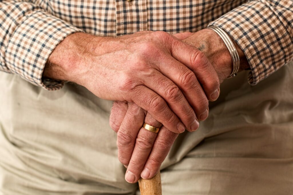 Ein älterer Menschen hält mit einer Hand die andere