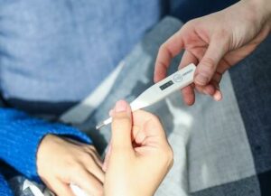 Frau mit Fieberthermometer in der Hand