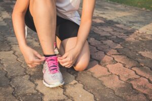 Frau mit Laufschuhen bindet sich eine Schleife