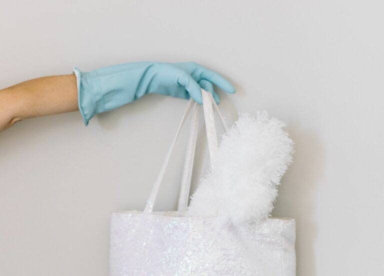 Hand mit Schutzhandschuh hält eine Tasche mit Staubwendel