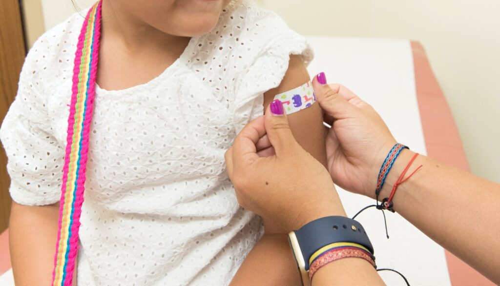 Kind wird Pflaster nach der Impfung auf den Arm geklebt