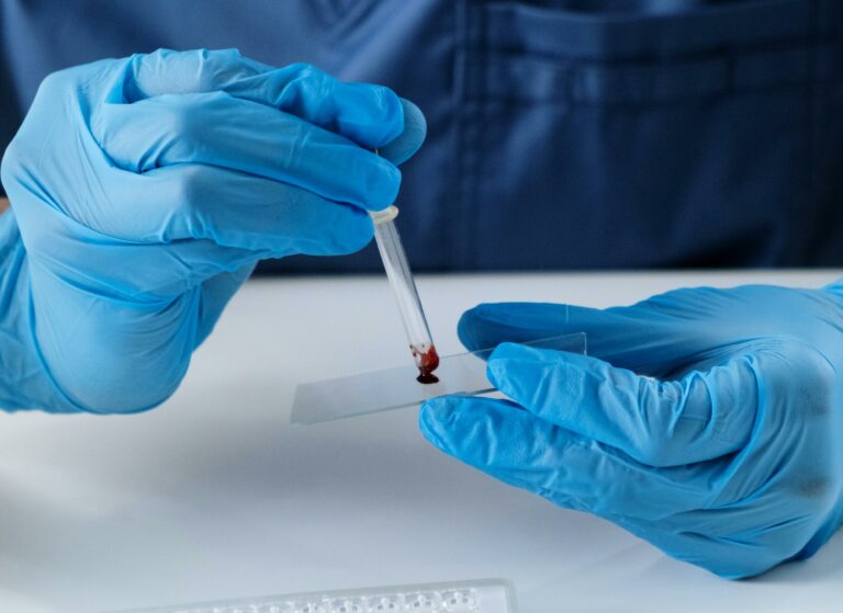 Blut wird von einer Pipette auf eine Glas getropft